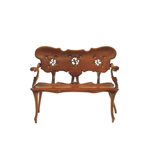 The BD Calvet Bench presents a striking example of craftsmanship, with flowing organic lines and delicate floral carvings along the backrest. Its elegant silhouette combines sculptural details with practical seating functionality.