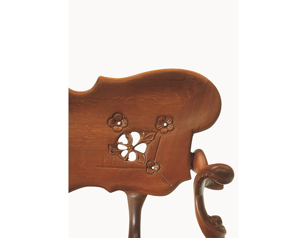 The BD Calvet Bench backrest features delicate floral carvings, highlighting intricate details, soft curves, and artisanal craftsmanship that emphasize the natural forms defining the piece’s distinctive character.