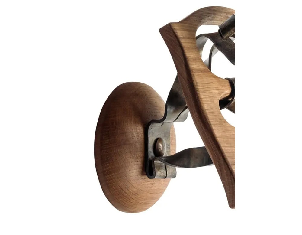 Detail of the BD Calvet Hanger showing the rounded wooden wall mount, iron bracket, and carved oak base with curved elements.
