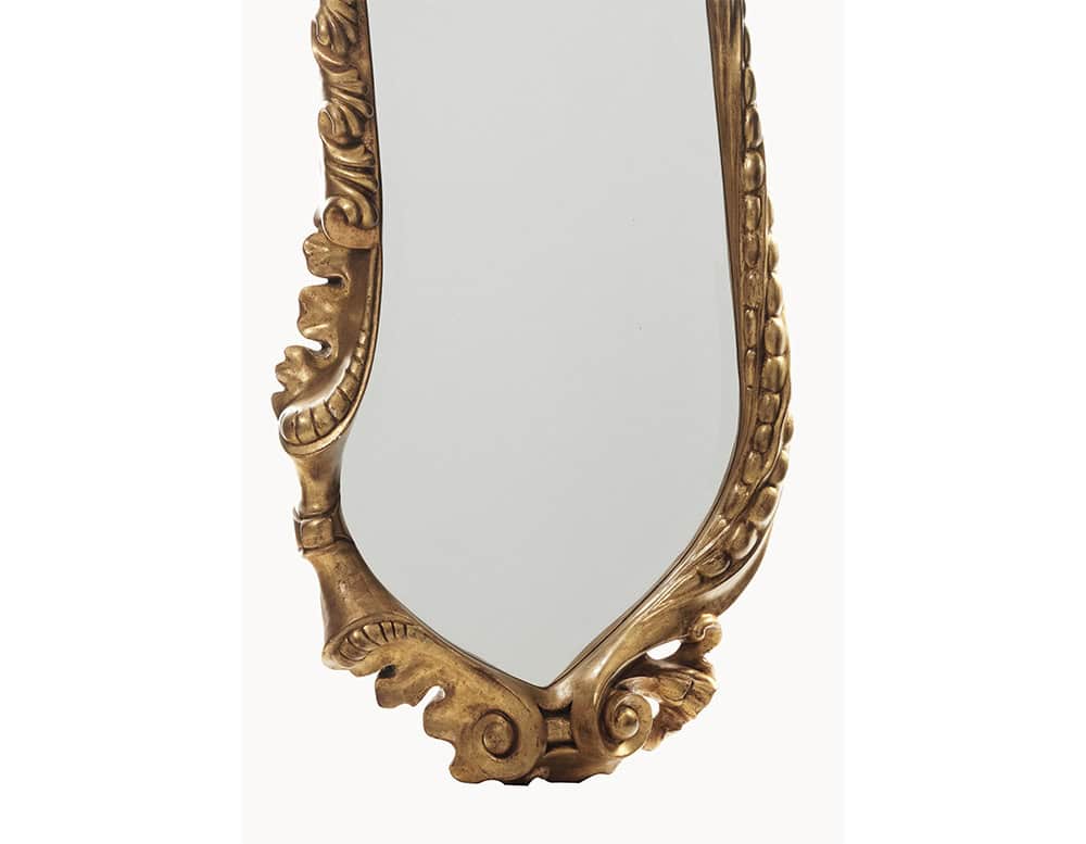 The BD Calvet Mirror features an intricate lower section where vegetal-inspired carvings flow seamlessly into the base. The golden finish enhances the mirror's ornate craftsmanship while maintaining a soft, reflective elegance.