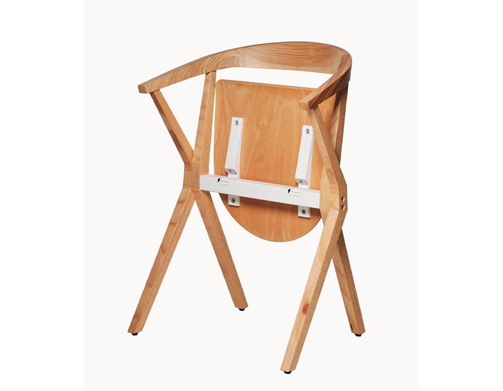 The chair’s folding seat mechanism is seamlessly integrated into its natural wood structure, combining functionality with elegant design.