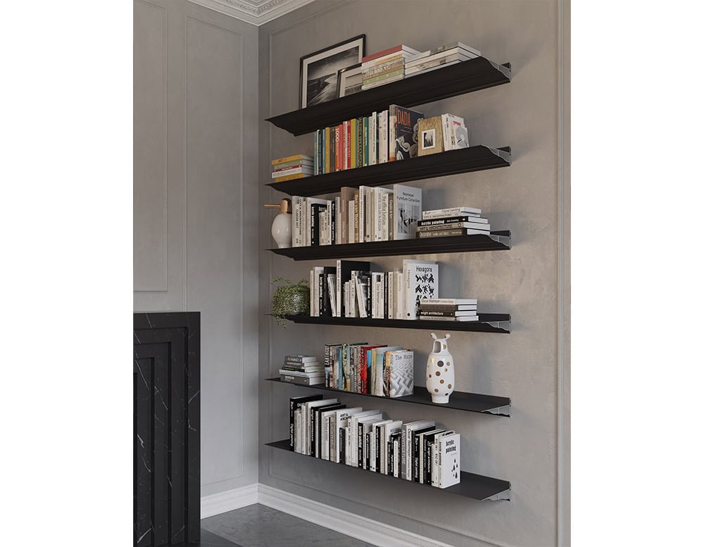 The BD Cornisa Shelf system is presented in a matte black finish, mounted on a grey textured wall, with the staggered shelves filled with an eclectic mix of books, ceramics, and greenery, adding depth and interest to the corner space.