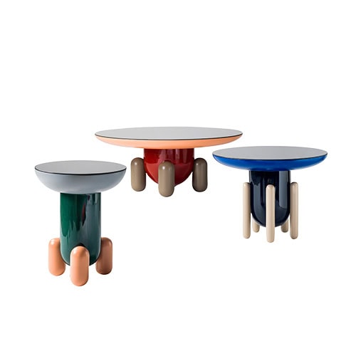 A playful trio of Explorer side tables in glossy finishes. The round trays feature soft edges in grey with peach legs, red with taupe legs, and blue with cream legs, adding a sculptural and tactile feel to the collection.