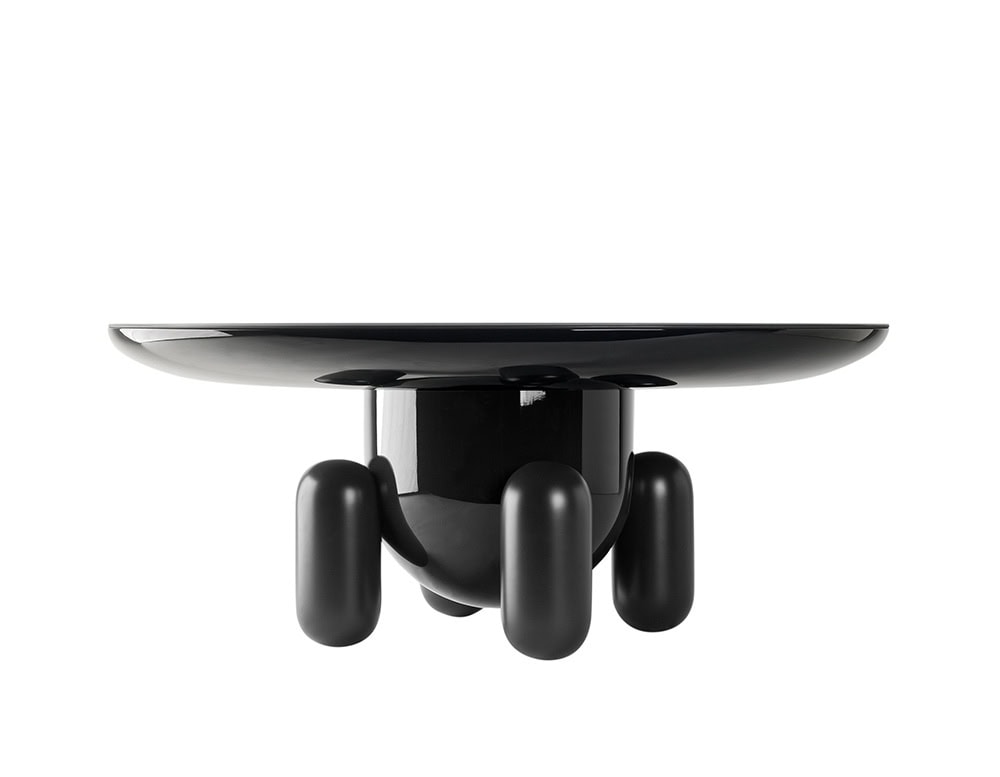 A low side table in glossy black with a bold, rounded silhouette. Its smooth top rests on playful cylindrical legs, giving the piece a sculptural yet approachable presence.