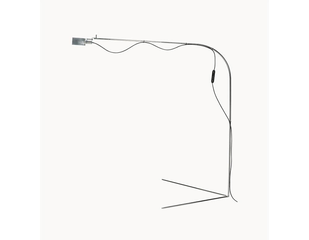 The BD Flamingo Floor Lamp features a slim, cantilevered structure in polished steel with a long, arched arm and a weighted base for balance. Its minimalist design is complemented by a visible black cord and inline switch.