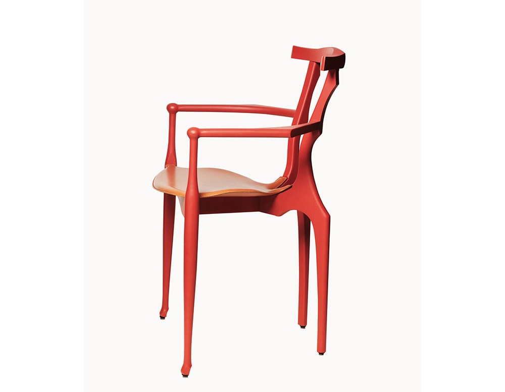 Three-quarter view of the red BD Gaulino Chair with a tan leather seat, emphasizing its sculptural frame, delicate curves, and handcrafted detailing.