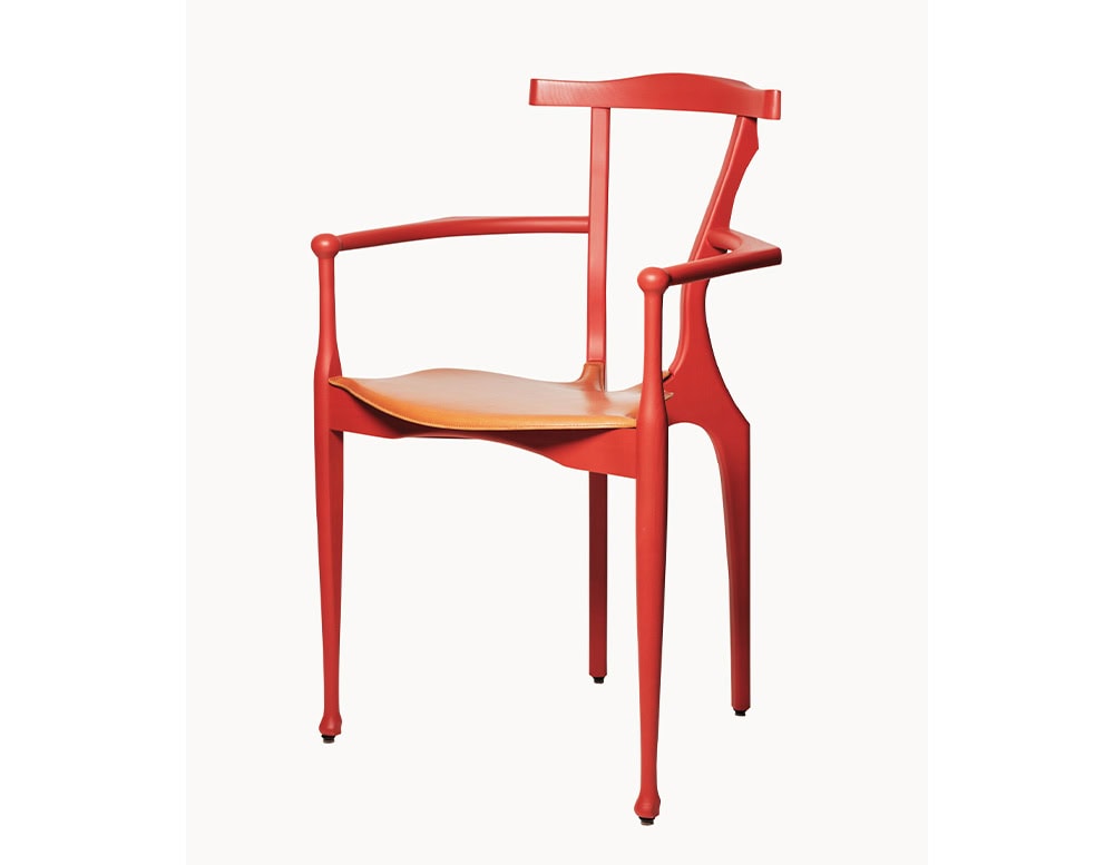 A red BD Gaulino Chair with a tan leather seat, showcasing its sculptural armrests, sinuous lines, and elegantly tapered legs.