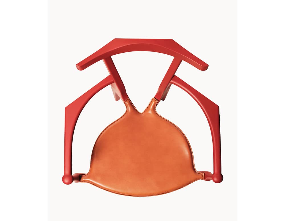 A bold red BD Gaulino Chair with a tan leather seat, seen from above, emphasizing its sculptural frame, curved arms, and distinctive triangular backrest.