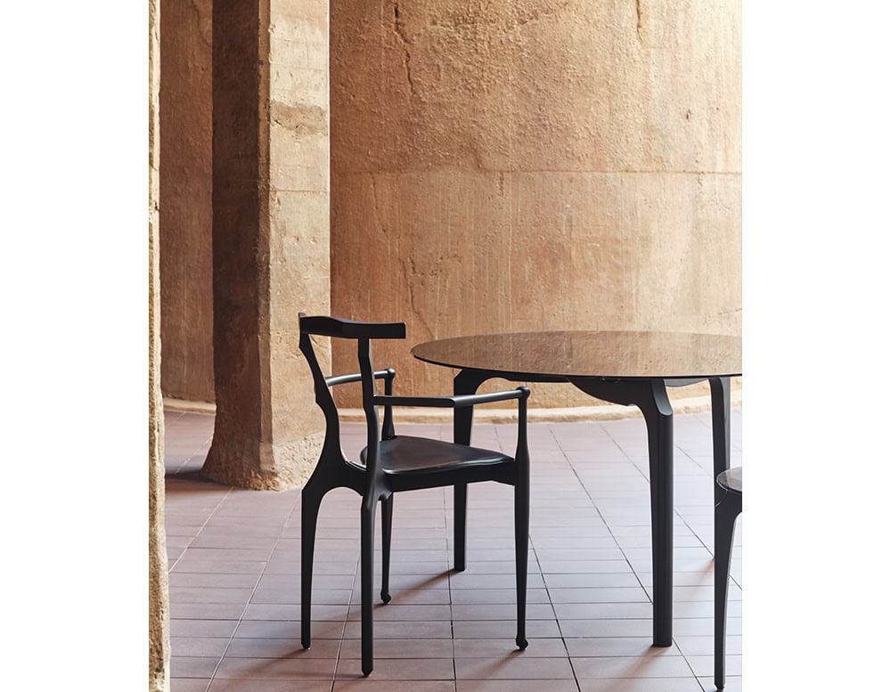 A black BD Gaulino Chair pairs with a matching table. Its sculpted frame and leather seat bring elegance and character to the warm-toned setting.