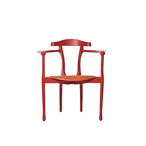 Elegant red chair with flared legs, curved backrest, and slender armrests. The warm tan leather seat enhances its refined silhouette, blending craftsmanship with sculptural beauty.