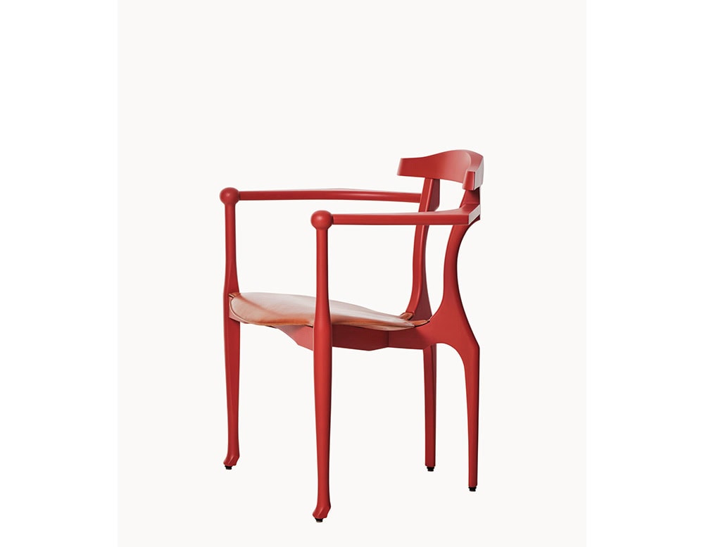 Red sculptural frame with gracefully curved arms and slender legs, paired with a smooth tan leather seat. The blend of fluid lines and bold color gives it a timeless, artistic presence.