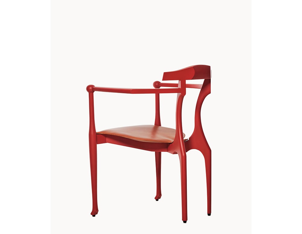 Curved red ash wood frame with a sculpted backrest and slender arms, paired with a smooth tan leather seat. The silhouette blends classical inspiration with contemporary elegance.