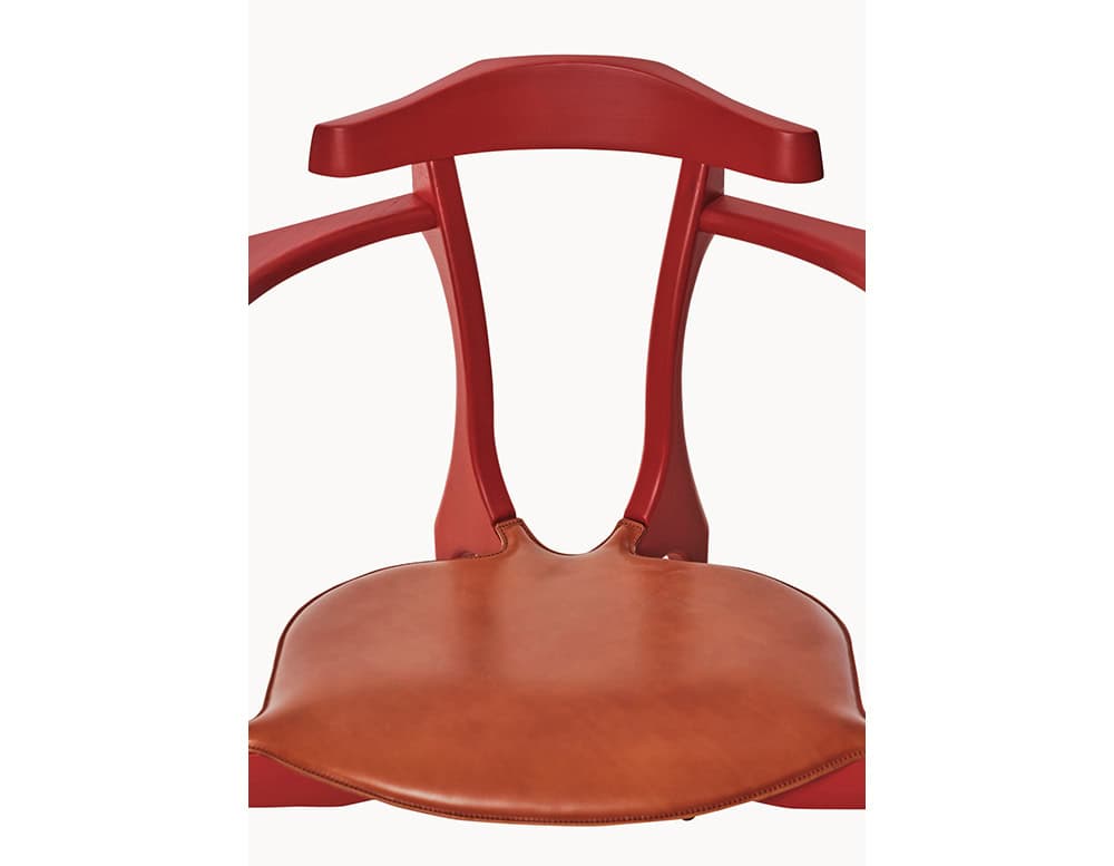 Gaulino Easy Chair highlighting its elegant curved backrest, sculpted red wooden frame, and smooth tan leather seat. A refined balance of classic craftsmanship and contemporary form.