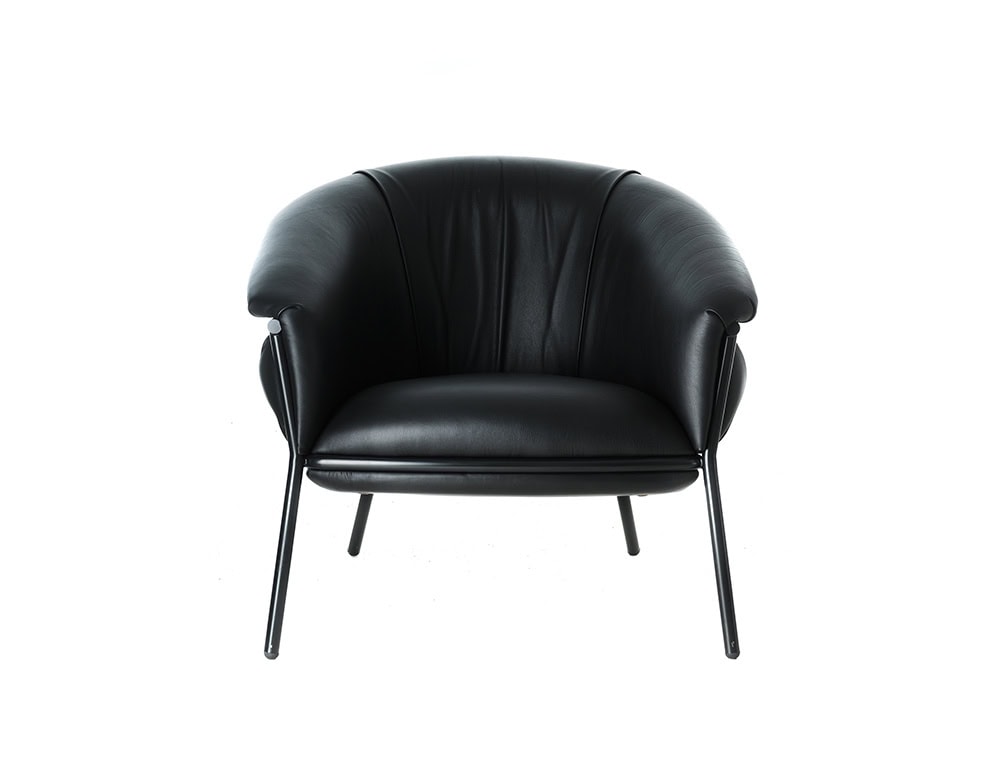 Direct front view of the BD Grasso Armchair in black leather emphasizes its rounded, ample cushions within a slender tubular frame. The voluminous upholstery seems to overflow slightly beyond the structure, creating a playful and inviting silhouette.