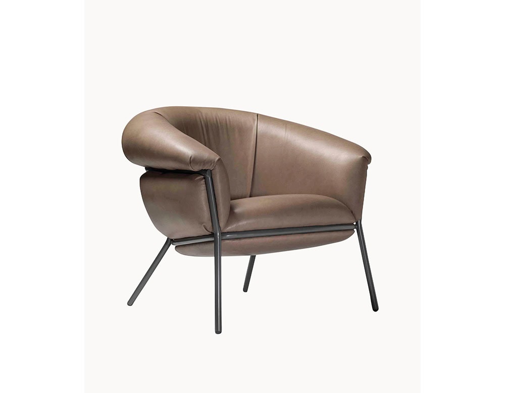 The BD Grasso Armchair features a plump taupe leather seat with ample padding that visually spills over its frame. Slim black metal legs and structure create a precise contrast to the chair’s soft, voluminous form.