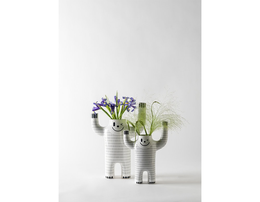 Playful ceramic piece shaped like a cheerful, waving figure. With its whimsical expression and sculptural form, it brings joy and personality to any space.