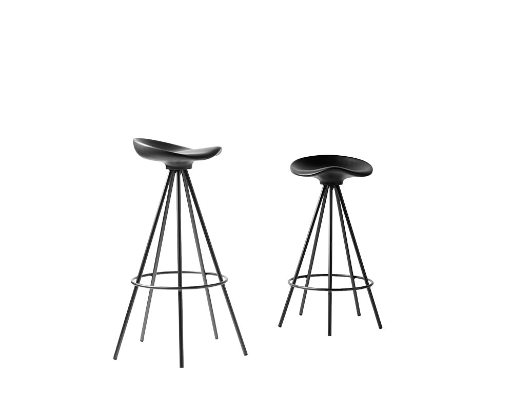 Two Jamaica Stools in matte black, featuring sculpted seats and flared metal legs with integrated footrests. Their monochrome finish and ergonomic form offer a sleek, contemporary seating option.