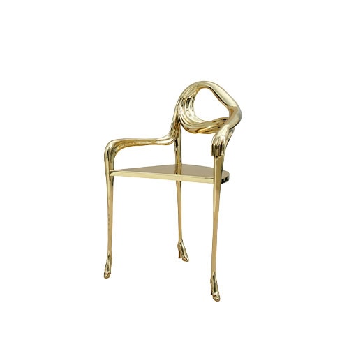 An armchair crafted in polished bronze, where the backrest melts seamlessly into an arm and hand. The fluid structure rests on slender legs, detailed with delicate shoe-like feet.