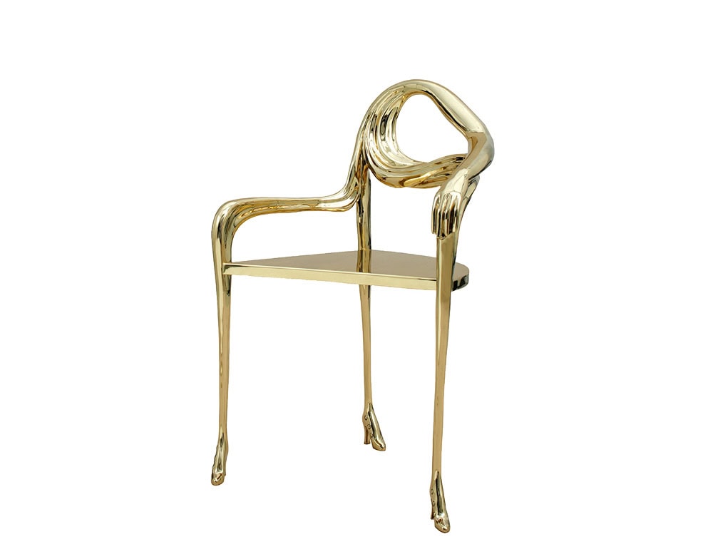 The BD Leda Armchair in polished brass transforms furniture into art. Its design blends sculptural lines with functional purpose, featuring elongated limbs and a hand-shaped armrest that wraps gracefully around the back.