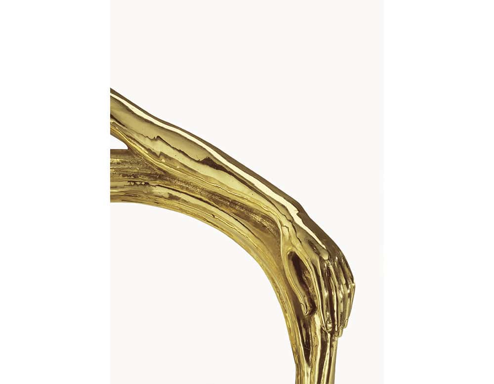 A detailed view of the BD Leda Armchair’s backrest highlights its sculptural elegance. The golden surface captures the delicate gesture of a hand resting gracefully, turning a functional element into a work of art.