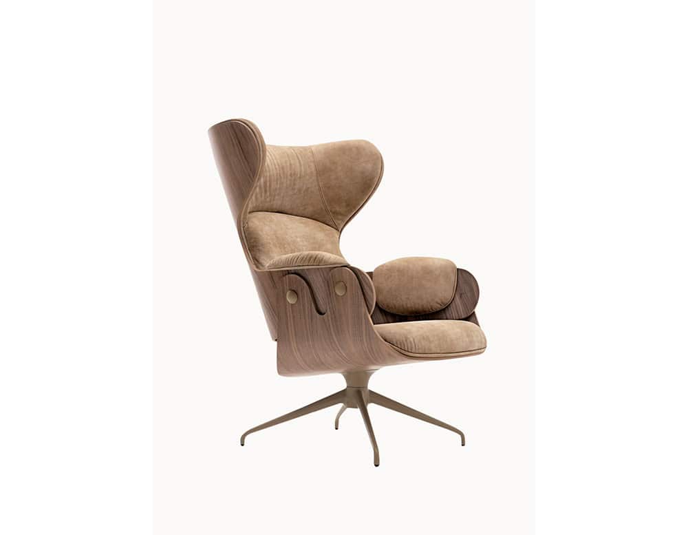 Lounger Armchair with a curved walnut wood shell and soft beige suede upholstery. The sculptural form, plush cushions, and bronze swivel base offer a perfect blend of comfort and modern sophistication.