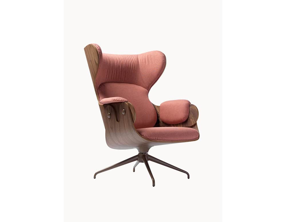Lounger Armchair with a molded wood shell and soft rose-pink upholstery. Its curved silhouette, cushioned comfort, and elegant swivel base combine to create a modern yet inviting statement piece.