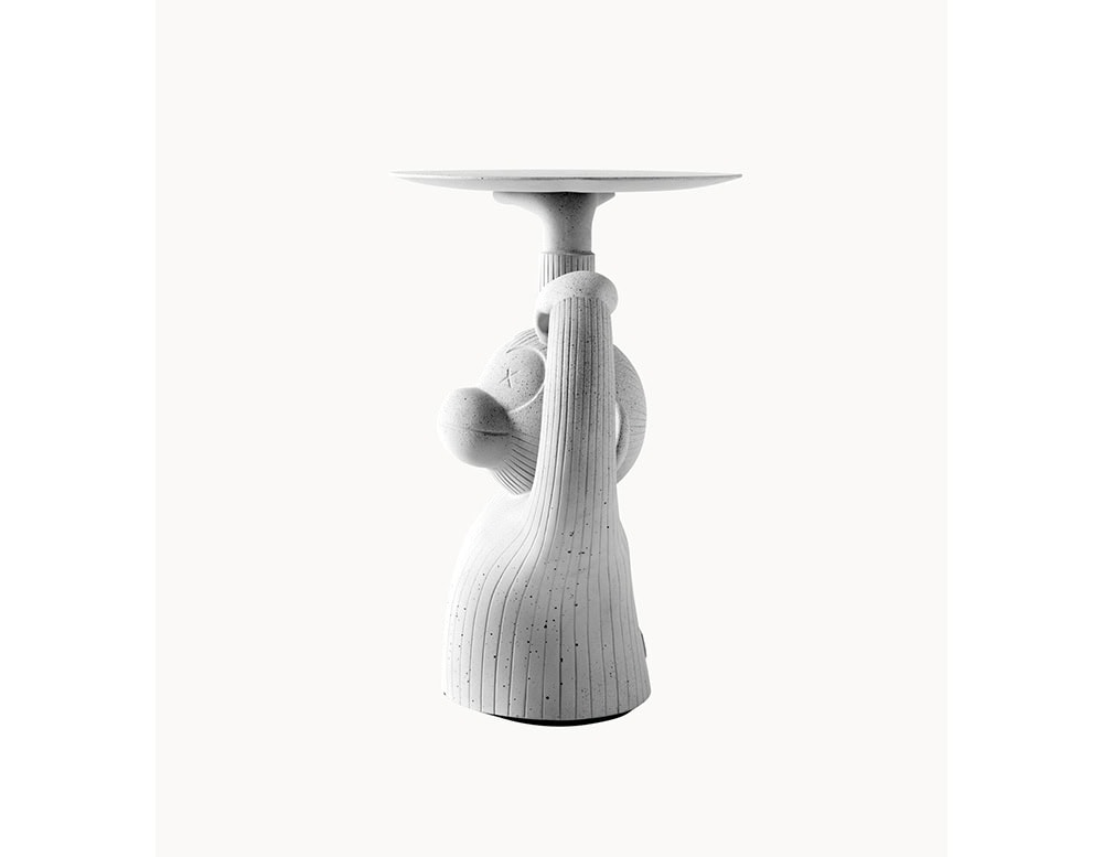 A side view of the BD Monkey Side Table reveals the playful gesture of the figure holding the tray above its head. The concrete texture and detailed grooves create a tactile quality, blending sculptural form with practical function.