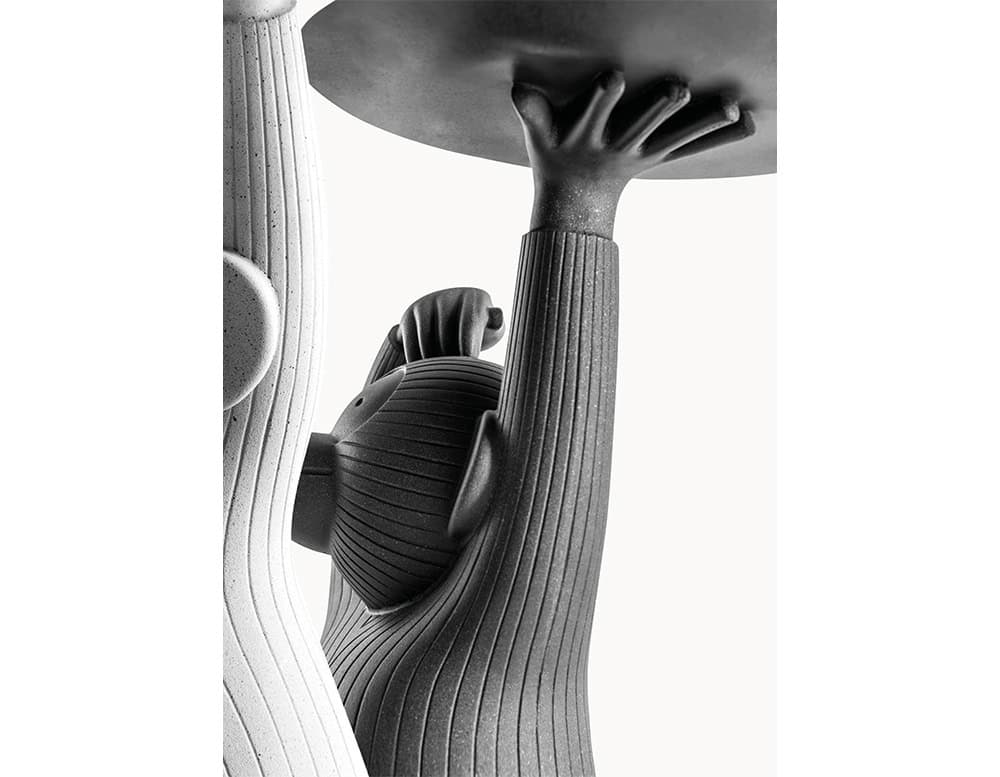 Two Monkey Side Tables, one in white and one in dark grey, highlighting their textured resin surfaces and playful sculpted forms. Each figure holds a circular tabletop with a gesture that feels both natural and expressive.