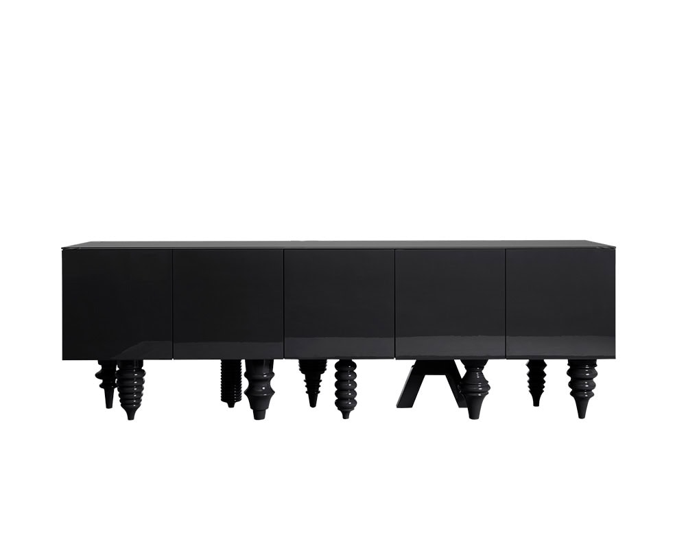 A sleek black cabinet with a polished finish that highlights its smooth surface. The design is minimalist at the top, while the base introduces a playful mix of legs in different carved shapes, creating a bold visual contrast.