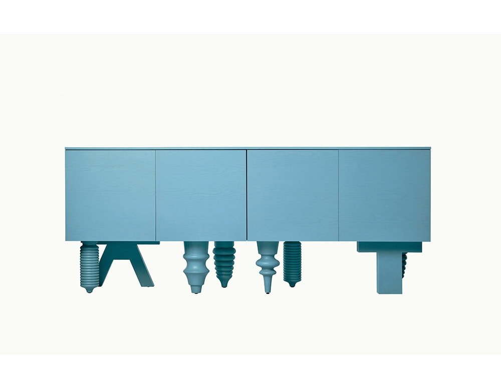 Sky blue cabinet with flush-front doors, supported by a bold mix of carved and architectural legs in matching finish, creating a playful and structured visual rhythm.