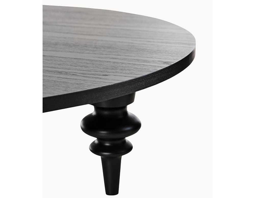 Multileg Coffee Table detail view showing sculpted black leg and round wood top in rich dark grain. Expressive, modern, and full of personality.