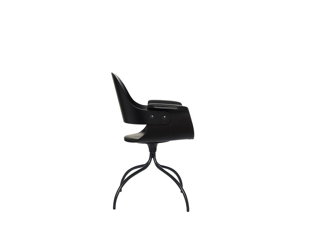 Sculpted wood armchair in deep matte black with curved contours, subtle armrests, and a polished seat. Anchored by gracefully branching metal legs that create a sense of organic motion.