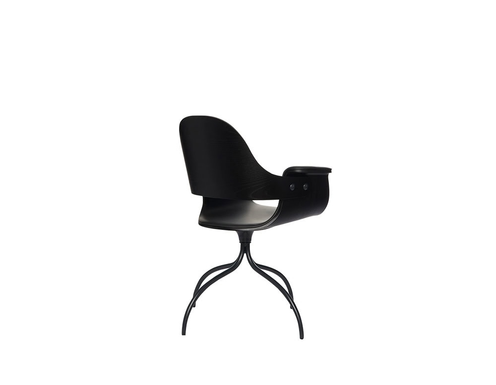 Curved wood chair in matte black with a wraparound backrest and gently flared arms. Supported by sculptural, branch-like metal legs that add fluidity and visual balance to its sleek form.