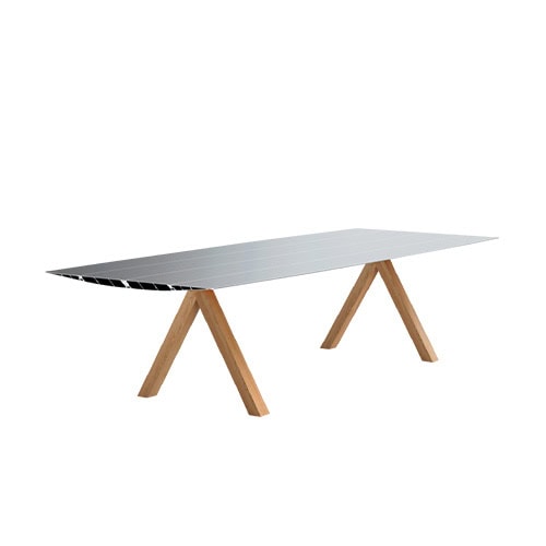 The BD Table B showcases a long, aerodynamic aluminum surface with exposed honeycomb edges. Its solid oak trestle legs provide sturdy support while introducing a warm, natural element to the contemporary design.