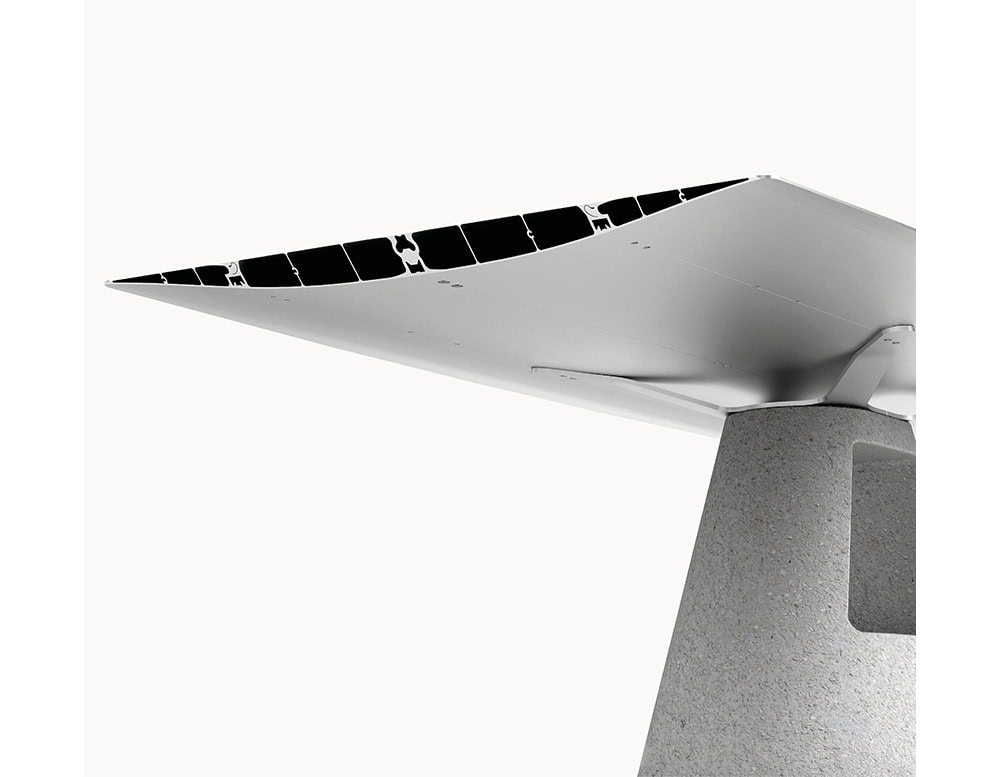 The BD Table B features a sleek aluminum tabletop resting on a robust concrete base. The pairing of smooth, light-toned aluminum and textured grey concrete creates a refined contrast.