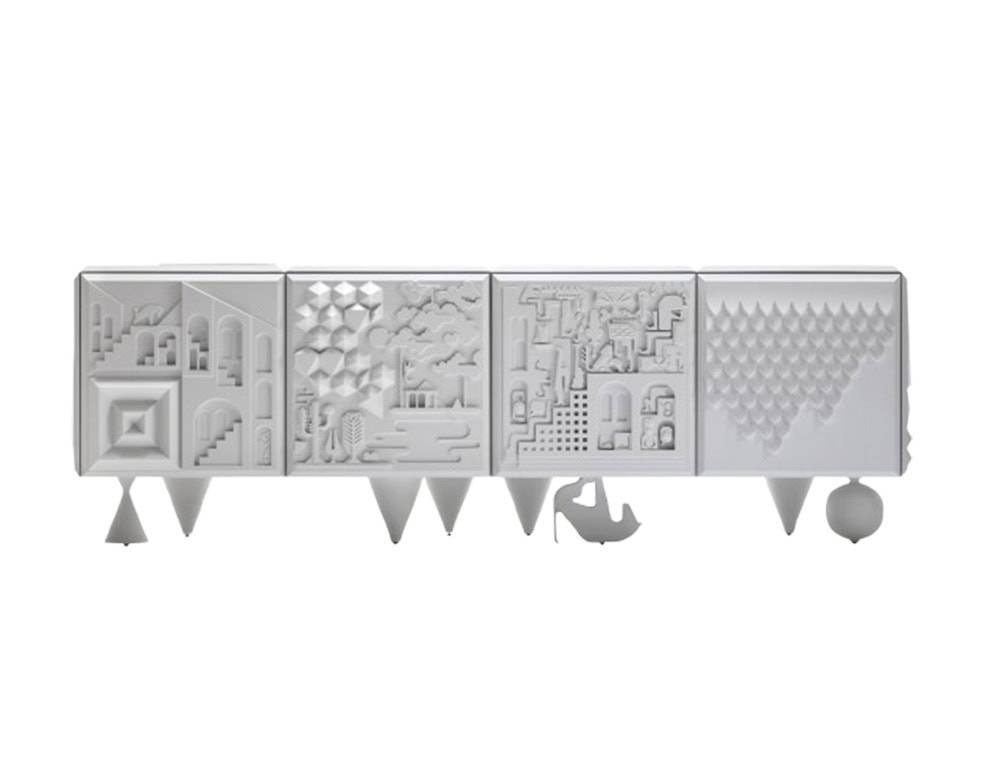 White cabinet with sculpted doors featuring whimsical reliefs of architecture, nature, and geometric forms. Supported by uniquely shaped legs, including a stiletto-like form, cone, and sphere, giving it a surreal and playful character.