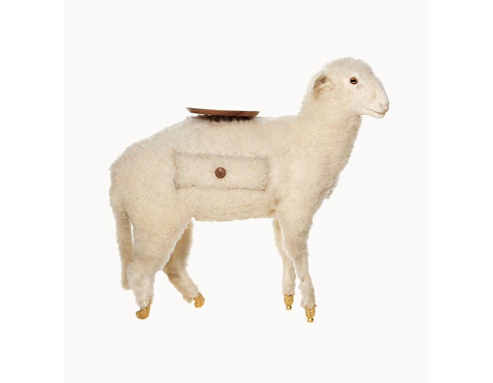 A whimsical and functional piece designed in the form of a lamb, featuring golden hoof details, a wooden tray on its back, and a small side pocket that adds playful practicality.