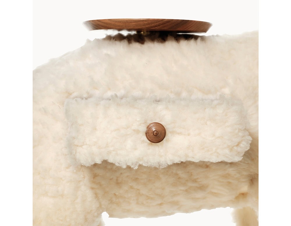 A close-up view of the playful lamb-shaped accessory highlights the small pocket detail on its side, complete with a wooden button closure, and the wooden tray positioned on its back.
