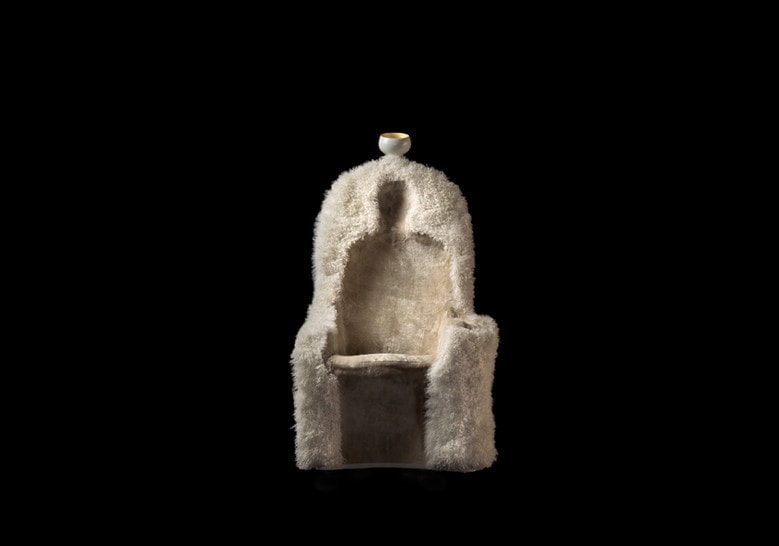 armchair made of sheepskin in the shape of a human silhouette in a white tone on a black background