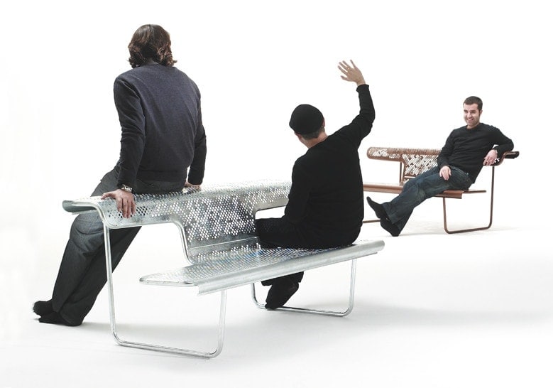 two benches with a table made of steel in a brown and silver tone with people in the background