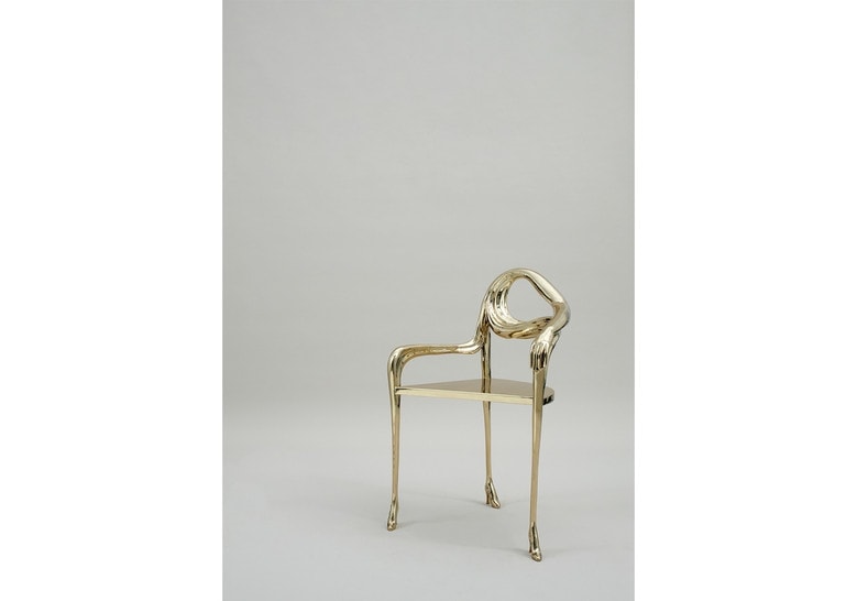 chair made in the shape of heels on its base and made of brass in a golden tone