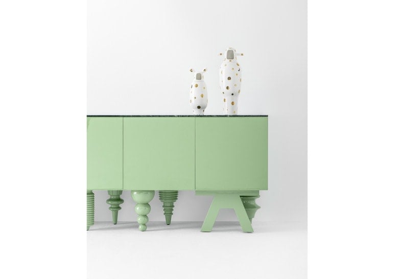 two small sculptures made of white ceramic with gilding on a piece of furniture in a room