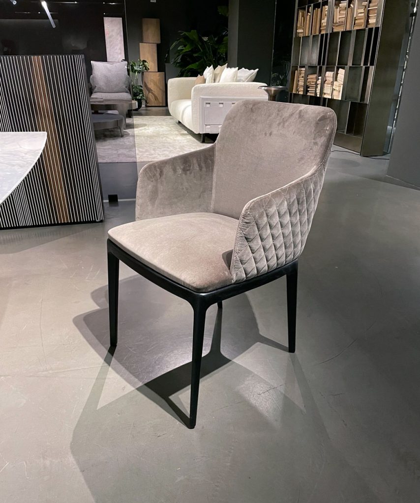 Dining chair made with a wooden base and upholstered in velvet with spike-shaped finishes in a light gray tone