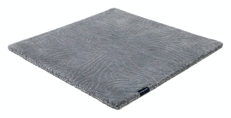 rug made of velvet and hand-braided in a dark blue tone with lines drawn in its design