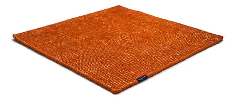 Handmade rug made of fine wool and fabrics in a orange tone on a white background