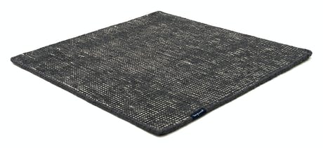 Handmade rug made of fine wool and fabrics in a dark gray tone on a white background