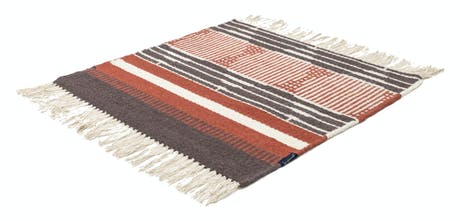 hand-woven rug with fabric in shades of red black and beige