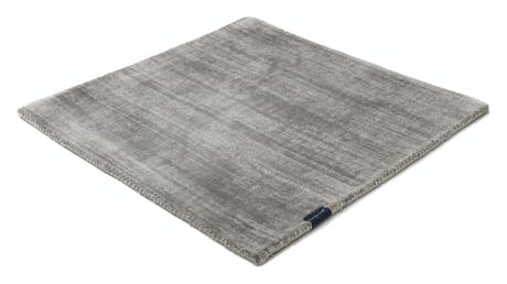 handmade rug in a light gray tone with white finishes on a white background