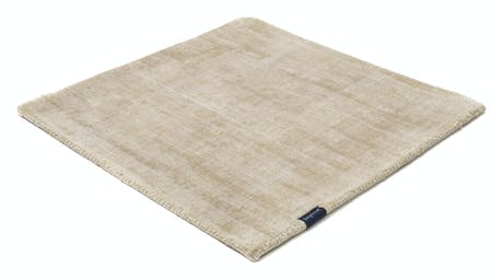 handmade rug in a sand color tone with white finishes on a white background