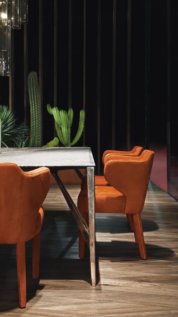 Three EX Tra Chairs upholstered in orange leather and four wood legs in a dining room.